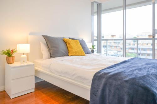 a white bed in a room with a large window at Modern Darling Harbour 2BR Apt Walk to Everything in Sydney