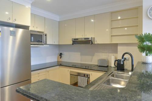 a kitchen with white cabinets and a stainless steel refrigerator at Modern Darling Harbour 2BR Apt Walk to Everything in Sydney