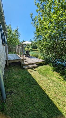 a wooden deck next to a lake with a picnic table at Lynstone Lakes in Bude