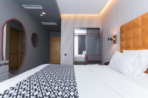 a bedroom with a large white bed and a mirror at Amante Narikala Boutique Hotel in Tbilisi City