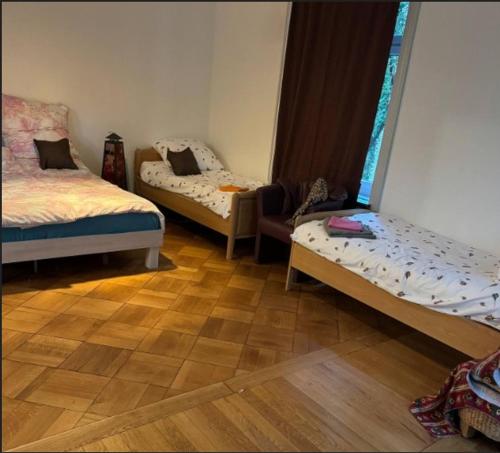 two beds in a room with a wooden floor at Großes Gruppen Zimmer 2min von Hbf Solothurn in Solothurn