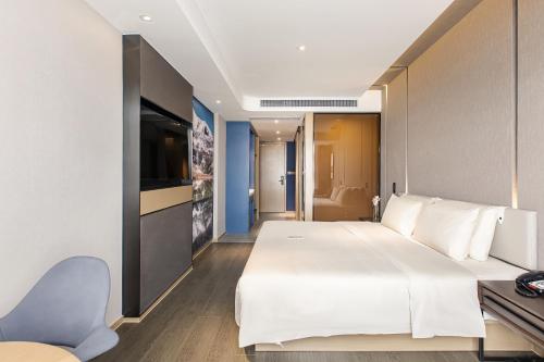 a bedroom with a large white bed and a chair at Atour Hotel Chengdu Yulin Huaxi in Chengdu
