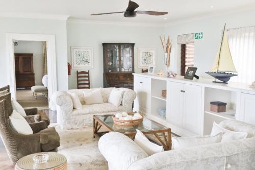 a living room with white furniture and a ceiling fan at Buccara Noetzie - Pezula Castle in Knysna