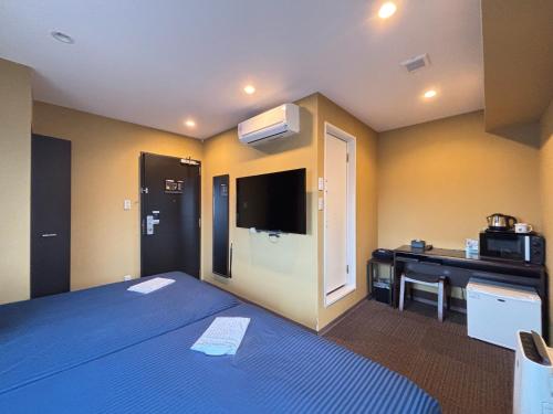 a room with a bed and a desk with a television at HOTEL LiVEMAX Fukuyama Ekimae in Fukuyama