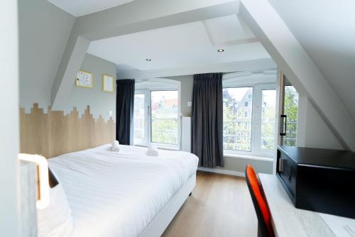 Un dormitorio con una cama blanca y un televisor. en The Crown Hotel, en Ámsterdam
