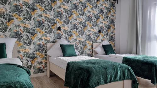 a room with two beds and a wall with a wallpaper at Q Apart PL 2 lub 3 pokojowe klimatyzowane apartamenty przy Manufakturze z garażem Gratis, FV in Łódź