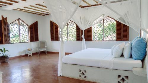 a bedroom with a bed in a room with windows at Kiboko Nyumba in Watamu
