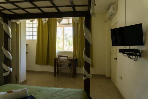 a bedroom with a bed and a table and a television at Don Giovanni Mancora in Máncora