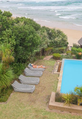 a row of chaise lounges are lined up next to a pool at Buccara Noetzie - Pezula Castle in Knysna