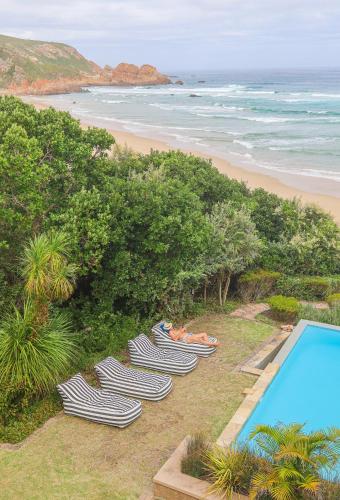 a group of chaise lounge chairs next to a beach at Buccara Noetzie - Pezula Castle in Knysna
