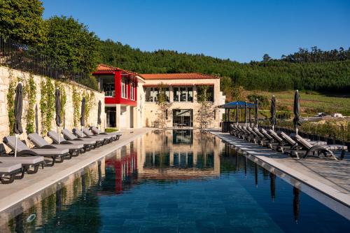 a pool with chaise lounges and chairs next to a building at Vila Gale Collection Ponte de Lima in Ponte de Lima