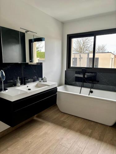 La salle de bains est pourvue de 2 lavabos, d'une baignoire et d'une fenêtre. dans l'établissement Villa moderne au coeur de la provence, à Pernes-les-Fontaines