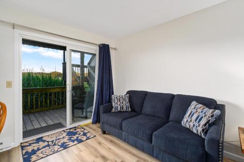 ein Wohnzimmer mit einer blauen Couch und einem Balkon in der Unterkunft Assateague Inn 106-S in Deep Hole