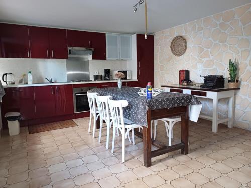 une cuisine avec une table, des chaises blanches et des armoires rouges dans l'établissement Sidobre, à Lacrouzette