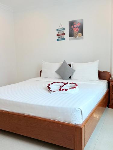 a bed with white sheets and red flowers on it at White Corner Hotel in Phnom Penh