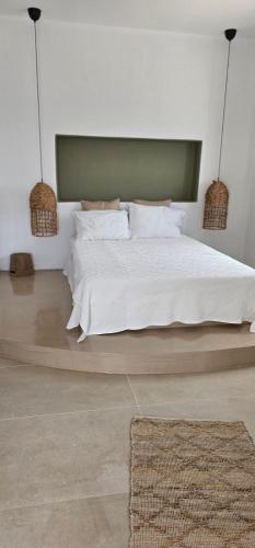 a bedroom with a large bed with white sheets and pillows at Almyriki in Mylopotas