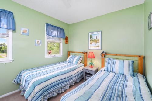 two beds in a bedroom with green walls and windows at Catch Of The Day in Deep Hole
