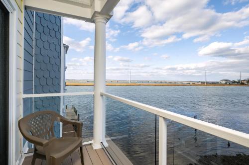 a chair sitting on a porch looking out at the water at Sunset Bay Villa 220 - Vista Costiera in Chincoteague
