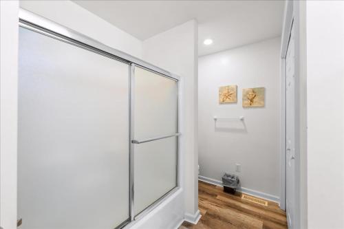 a glass shower in a white room with wood floors at Whispering Pines in Black Point Landing