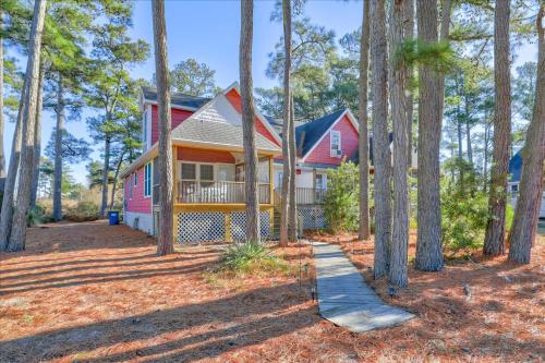 a red house with a porch in the woods at Whispering Pines in Black Point Landing
