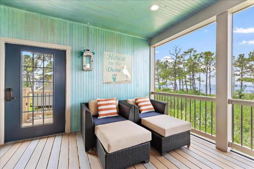 a screened in porch with two chairs and a table at House On The Dune in Deep Hole