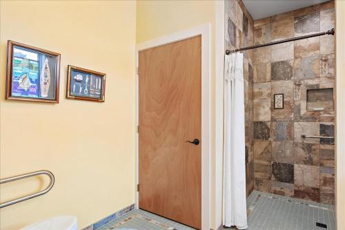 a bathroom with a shower and a wooden door at House On The Dune in Deep Hole