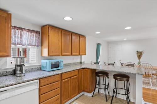 a kitchen with wooden cabinets and bar stools at Precious Time in Chincoteague