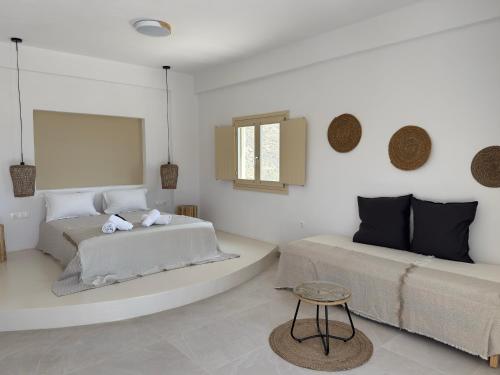 a white room with two beds and a table at Almyriki in Mylopotas