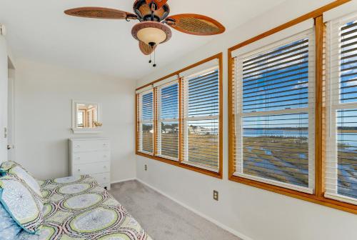 a bedroom with windows and a ceiling fan at Pony Swim Crossing in Black Point Landing