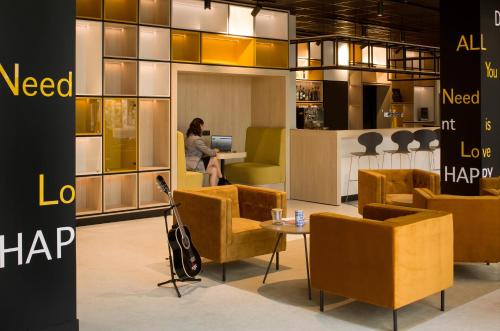 a woman sitting at a desk in a lobby with chairs at ibis Vichy in Vichy