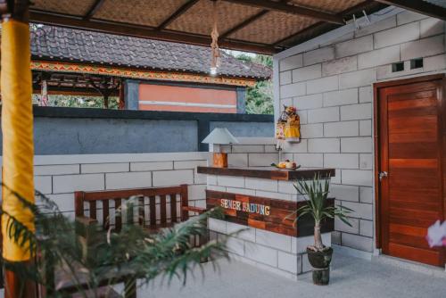 a house with a bench and a table with a lamp at Kubu Semer Badung in Nusa Lembongan