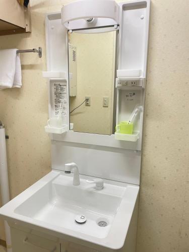 Un baño con un lavabo blanco y un espejo. en 千歳民泊桜華園, en Chitose