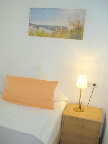 a bedroom with a bed with a lamp on a night stand at Pension Hermer in Grömitz