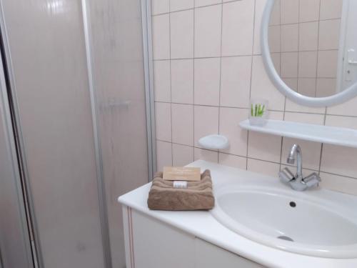 a white bathroom with a sink and a mirror at Gîte Acacia in Rosières