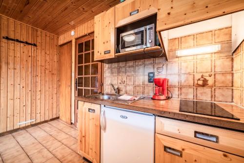 a kitchen with wooden cabinets and a microwave at La Flèche d'Or in Châtel