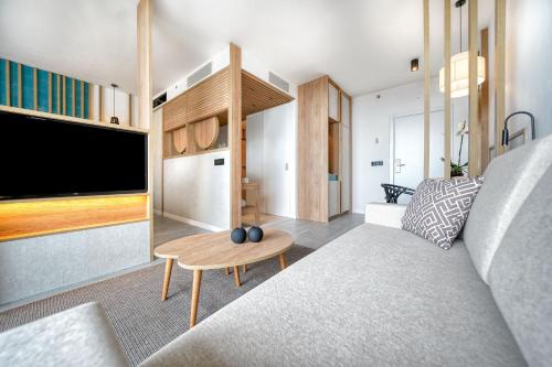 a living room with a couch and a tv at HOVIMA Suites Costa Adeje in Adeje