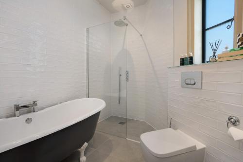 a white bathroom with a tub and a toilet at South Lodge, St Osyth Priory in Saint Osyth