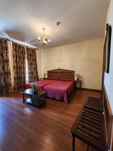 a bedroom with a red bed and a table at Jayca in Trujillo