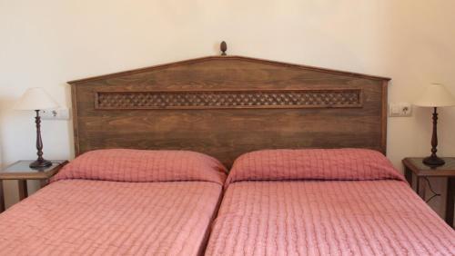 a bed with a wooden head board and two lamps at Jayca in Trujillo