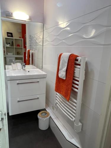 une salle de bain blanche avec une serviette orange et un lavabo dans l'établissement Bel Horizon, au pied de la plage du Sillon, à Saint-Malo