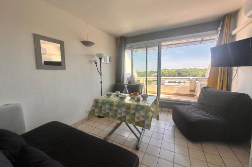 - un salon avec une table, un canapé et une fenêtre dans l'établissement Les Coquillages - Résidence avec piscine, au Grau-du-Roi