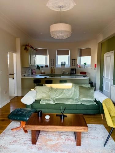 a living room with a green couch and a table at The Bunker, Golf Cottage in Prestwick