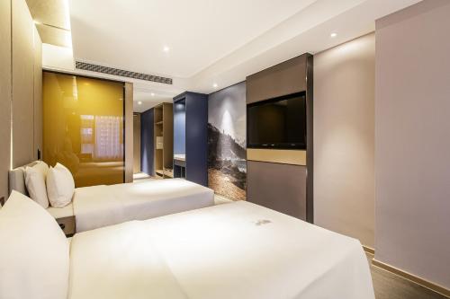 a hotel room with two beds and a flat screen tv at Atour Hotel Chengdu Yulin Huaxi in Chengdu
