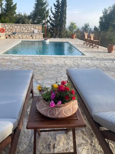 two chairs and a table with flowers on it next to a pool at The White House above Egremni in Athanion
