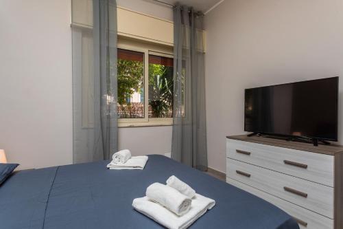 a bedroom with a tv and towels on a bed at Holiday Home Castello in Aci Castello