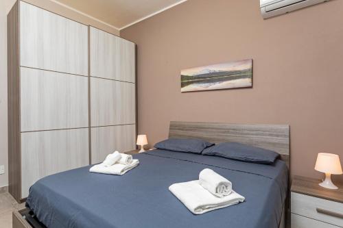 a bedroom with a blue bed with towels on it at Holiday Home Castello in Aci Castello