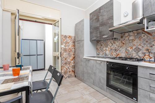 a kitchen with a stove and a table with a dining room at Holiday Home Castello in Aci Castello