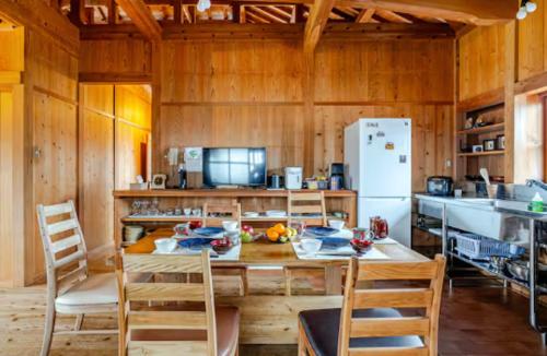 a kitchen with a table and chairs and a refrigerator at わらほんど in Naha