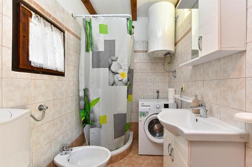 a bathroom with a toilet sink and a washing machine at Apartments Suzi 2381 in Peroj