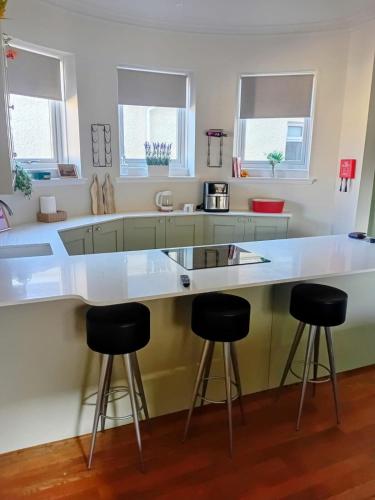 a kitchen with a large white counter and stools at The Bunker, Golf Cottage in Prestwick